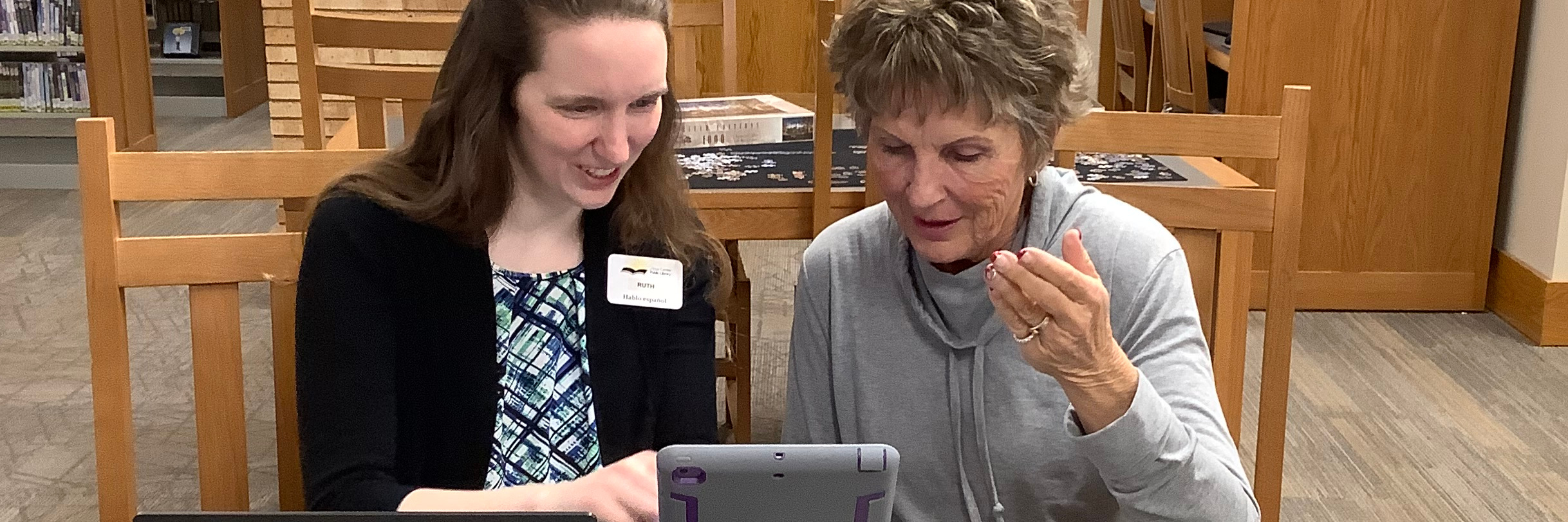 librarian helping a lady with a tech question on an iPad
